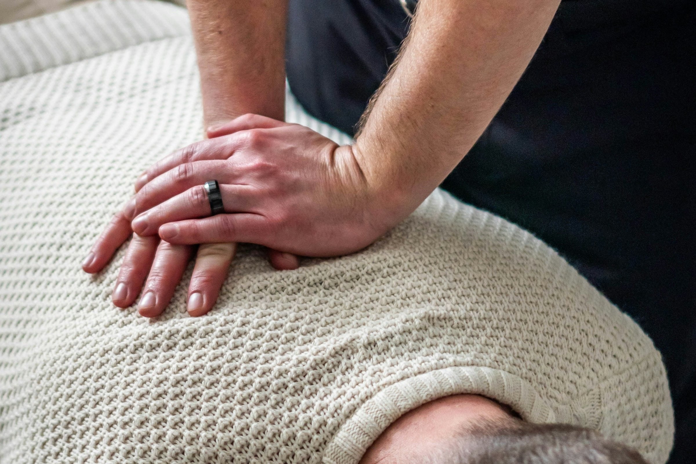 A practitioner's hands on a patient's upper back during treatment